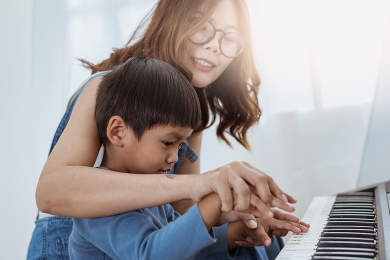 Piano teacher guiding a child at the keyboard