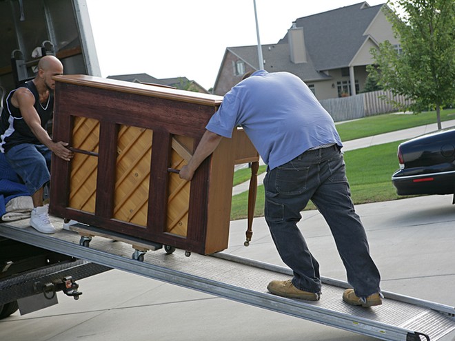 Piano movers loading an upright piano up a ramp